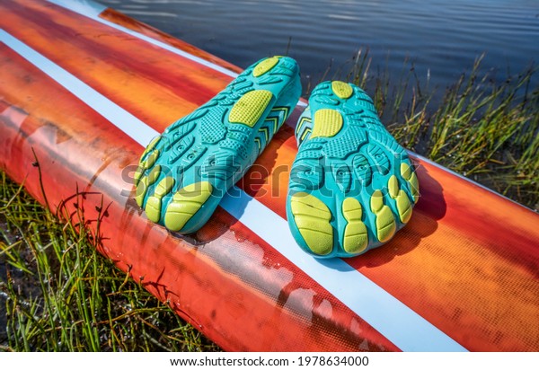 lightweight\
low-profile water shoes (soles up) for kayaking and other wet\
sports on a deck of a stand up\
paddleboard