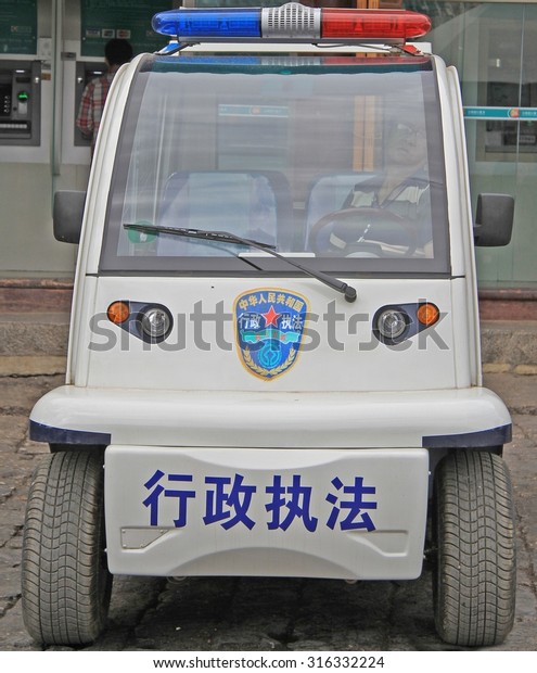 LIJIANG, CHINA - JUNE 10,\
2015: police officer is sitting inside police car on the street in\
Lijiang, China