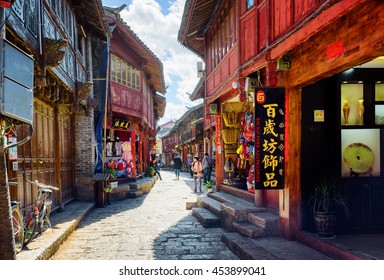 LIJIANG, YUNNAN PROVINCE, CHINA - OCTOBER 23, 2015: Scenic view of narrow street with souvenir shops in the Old Town of Lijiang. Beautiful wooden facades of traditional oriental Chinese houses.