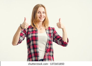 Like! Beautiful happy young woman shows thumbs up sign very well standing on a light background.