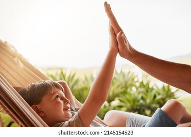 Like father, like son. Cropped shot of an unrecognizable man and his young son high fiving while lying outside on a hammock. - Powered by Shutterstock