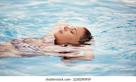 Like floating on a cloud. Cropped shot of a beautiful young woman relaxing in a swimming pool.
