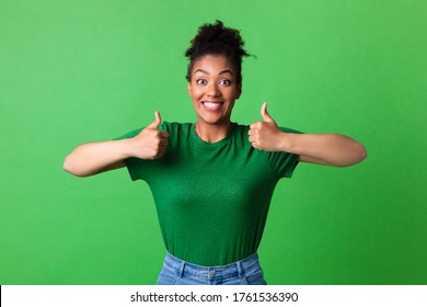 I Like It. Overjoyed black girl showing two thumbs up and widely smiling, isolated over green studio wall, copyspace - Powered by Shutterstock