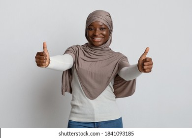 Like. Joyful Black Muslim Lady In Headscarf Showing Thumbs Up At Camera, Smiling African Woman In Hijab Recommending Great Offer, Gesturing Sign Of Approval, Standing Over Light Studio Background