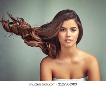 I Like My Hair With A Bit Of Kink. Studio Portrait Of A Beautiful Woman With Long Locks Posing Against A Grey Background.