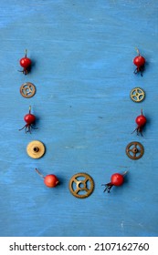 Like necklace from clock gears and wild rose hips on blue background