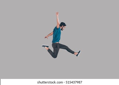 Like a rock star. Mid-air shot of handsome young man in cap jumping and gesturing against background 