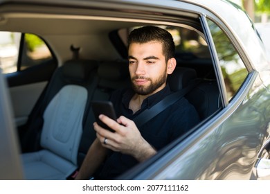 I Like Using My Rideshare App. Handsome Young Man Texting On The Smartphone While Going To His Destination With A Driver