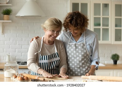 Like when I was little. Young woman grown daughter hug beloved older mother at kitchen table help cook. Adult kid retired mom make dough for domestic bakery together cooking by favorite family recipe