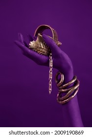 Lilac woman's hand with gold jewelry. Oriental Bracelets on a magenta painted hand. Gold Jewelry and luxury accessories, neon background closeup. High Fashion art concept 
