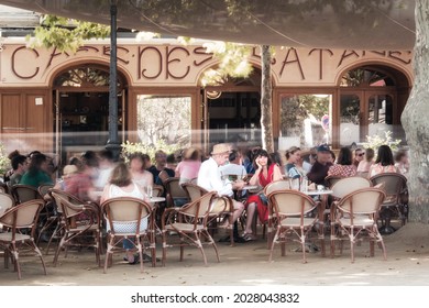 L'Ile Rousse, Corsica, France - 19th August 2021: A couple of holidaymakers relax outside the Café des Platanes at L'ile Rousse in the Balagne region of Corsica