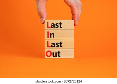 LILO last in and out symbol. Concept words LILO last in last out on wooden blocks. Beautiful orange table orange background. Businessman hand. Business and LILO last in and out concept. Copy space.