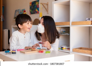 Liltle Preschooler Kid Playing Tetris Wood Puzzle With Teacher Educador Help Using Face Mask For Coronavirus Pandemic. Homeshooling. Learning Community. Montessori School