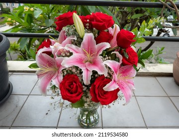 Lily Stargazer Flower Surrounded By Roses In A Glass Vase