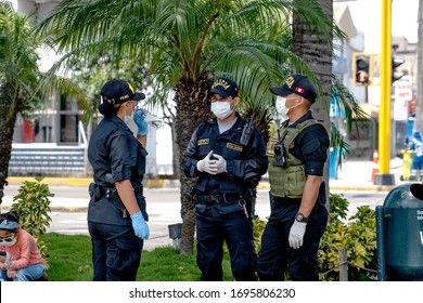 Lima, Peru - April 4 2020: Group Of Police Man And Woman Chatting And Wearing Masks And Gloves Amid Coronavirus Outbreak In South America. Officer Patrolling The Streets At COVID-19 Times.