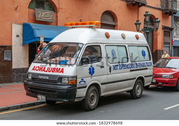 Lima, Peru - December\
4, 2008: Closeup of white ambulance van in street. Orange-brown\
facade as backdrop. 
