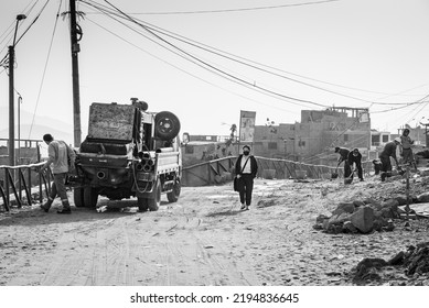 LIMA, PERU - JUNE 15, 2022: Black And White Photo Of A Young Person Coming Home From Work With Construction Workers In The Bello Horizontale Neighborhood, Part Of The Villa El Salvador Shantytown.