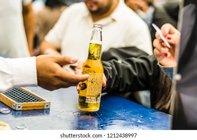 Lima, Peru - October 5th 2018: The Waiter Delivers Ice Cold Beer In Exchange For A Ticket At A Party At Noon.