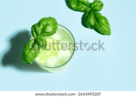 Lime Basil Mocktail with ice on blue background, top view, copy space. Green summer cocktail drink, refreshing tonic, citrus detox water. Basil smash.