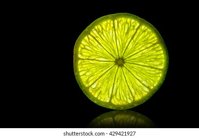 Lime Slice Backlit Isolated On A Black Background With Reflection. Design Element