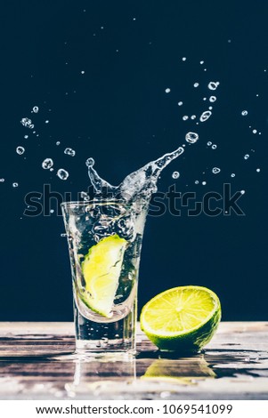 Lime slice falls into a glass with alcohol, gin, tequila, vodka
