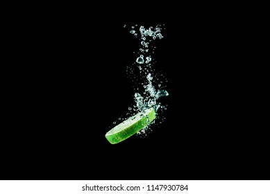 Lime Slice Falls Into The Water With Air Bubbles On A Black Background
