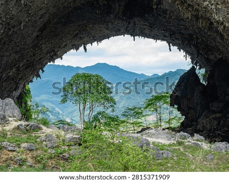Limestone cave arch framing distant green mountains and trees in Hechi Guangxi