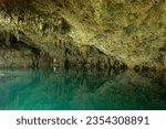 Limestone cenote cave of Yucatan with blue transparent water and stalactites and mirror reflection