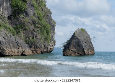 Limestone cliffs rising above waves on tropical beach