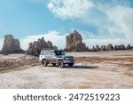 Limestone prehistoric chimneys at the bottom of dried lake and offroad vehicle, salt lake Abbe, Dikhil region, Djibouti