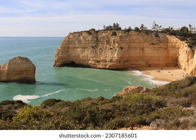 Limestone rock cliffs and rock in the Atlantic Ocean with a small sandy beach on a sunny winter day along the Seven Hanging Valleys Trail in southern Portugal.