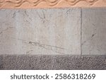 Limestone wall with fossil of extinct genus of large, straight-shelled cephalopod from the Ordovician period, Granite strip along the bottom edge, Cement wall with wavy line decoration painted orange