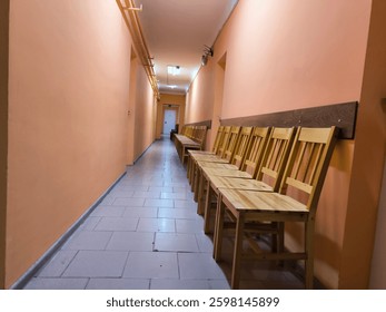 Liminal space presented by clean corridor with perfectly aligned under the wall chairs 