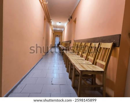 Liminal space presented by clean corridor with perfectly aligned under the wall chairs 