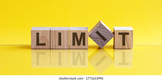 limit word written on wood block. limit text on table, yellow background, concept.
