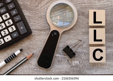 Limited Liability Company LLC Business Concept Background. Text On Wooden Blocks Near Black Magnifying Glass