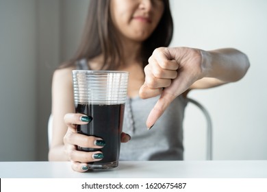 Limits Sugar Diet In Food Concepts. Young Woman Showing Bad Hand Symbol To Soft Drink Soda That Have High Sugar.