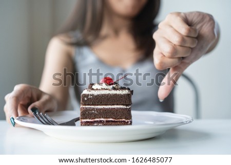 Limits sugar diet in food concepts. Young woman showing bad hand symbol to cake that have high sugar.