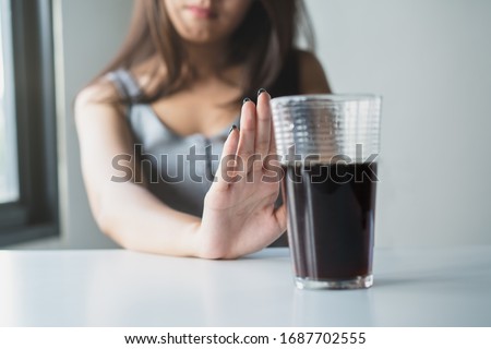 Limits sugar diet in food concepts. Young woman showing bad hand symbol to soft drink soda that have high sugar.