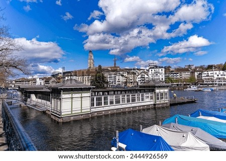 Limmat river with pier, moored boats and skyline of the medieval old town at Swiss City of Zürich on a sunny spring day. Photo taken April 2nd, 2024, Zurich, Switzerland.