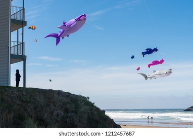 Lincoln City, Oregon - October 6, 2018: Silhouette Of A Person Standing On A Hill Watching A Large Purple Whale Kite Flying In Windy Blue Sky Along The Ocean Coast. 