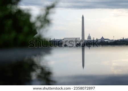 The Lincoln Memorial, Washington Monument, and US Capitol reflect off of a stone structure from across the Potomac River in Arlington, Virginia.