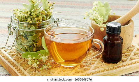 Linden herbal  tea with lime tree bloom and glass can with dried herb nearby on rustic wooden cutting board, backlit, closeup, copy space, alternative medicine and naturopathy concept - Shutterstock ID 1686849376