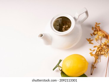 Linden Tea With Lemon, Fresh Drink, Green Leafy Lemon Next To White Porcelain Teapot On White Isolate Background, A Cup Full Of Tea With Sliced Lemon