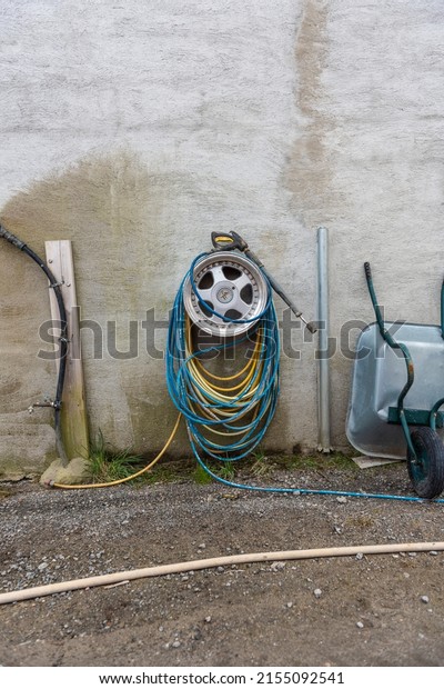 Lindesnes, Norway - April 16 2022: Water hose\
hanging from a sports car\
rim.