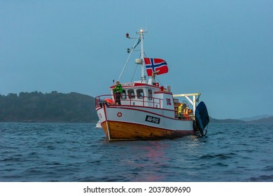 Lindesnes, Norway - August 07 2021: A Traditional Small Wooden Fishing Trawler With A Large Norwegian Flag.