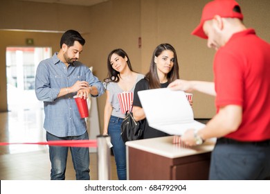 Line of annoyed people waiting to see a movie while an employee at the cinema theater looks at some list