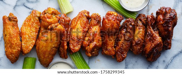 line of buffalo chicken wings drenched in\
different sauces
