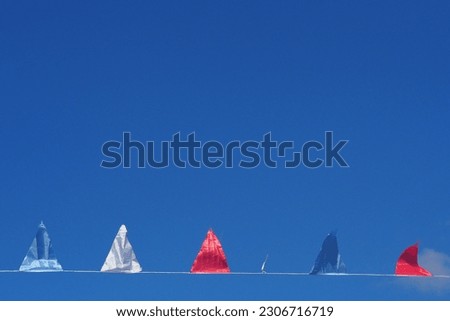 A line of buntings in blue white and red being blown by the wind against blue sky as background with space for runaround or wraparound text 