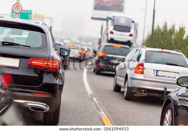 Line of cars and truck standing
on road in rush hour. Vehicles with lighting brake lights waiting
in traffic jam. Automobiles driving slow on road from
back.